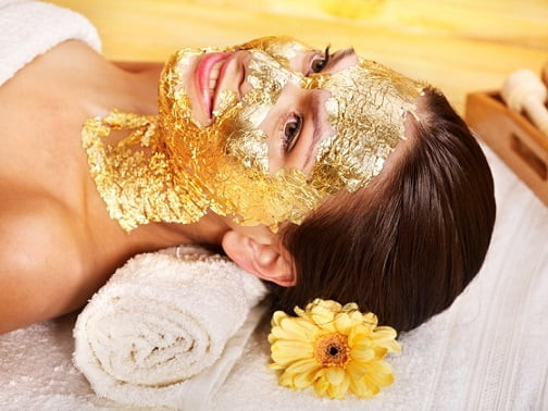 Woman getting gold facial mask.